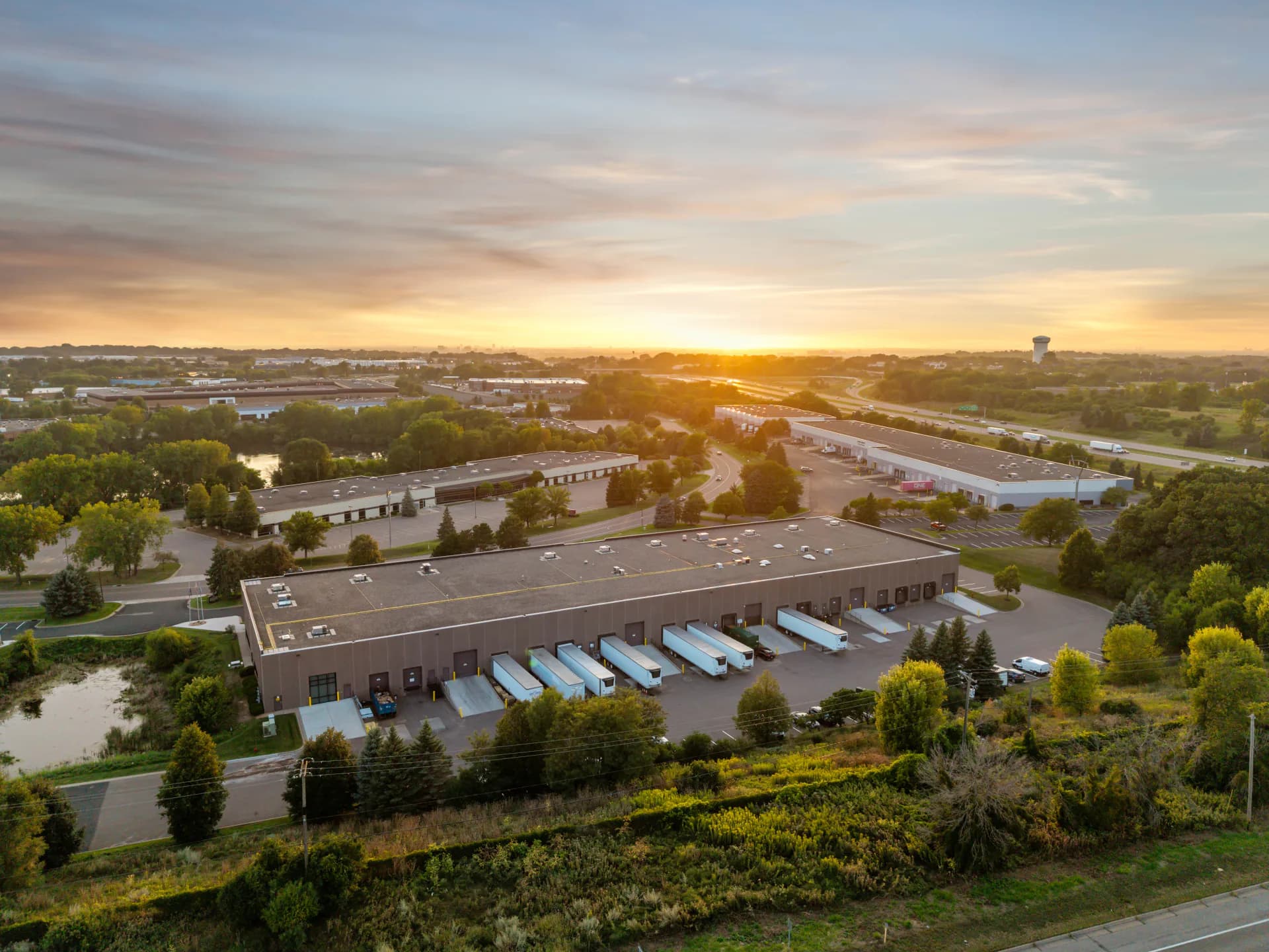 Aerial view over logistics warehouses and loading areas at golden hour