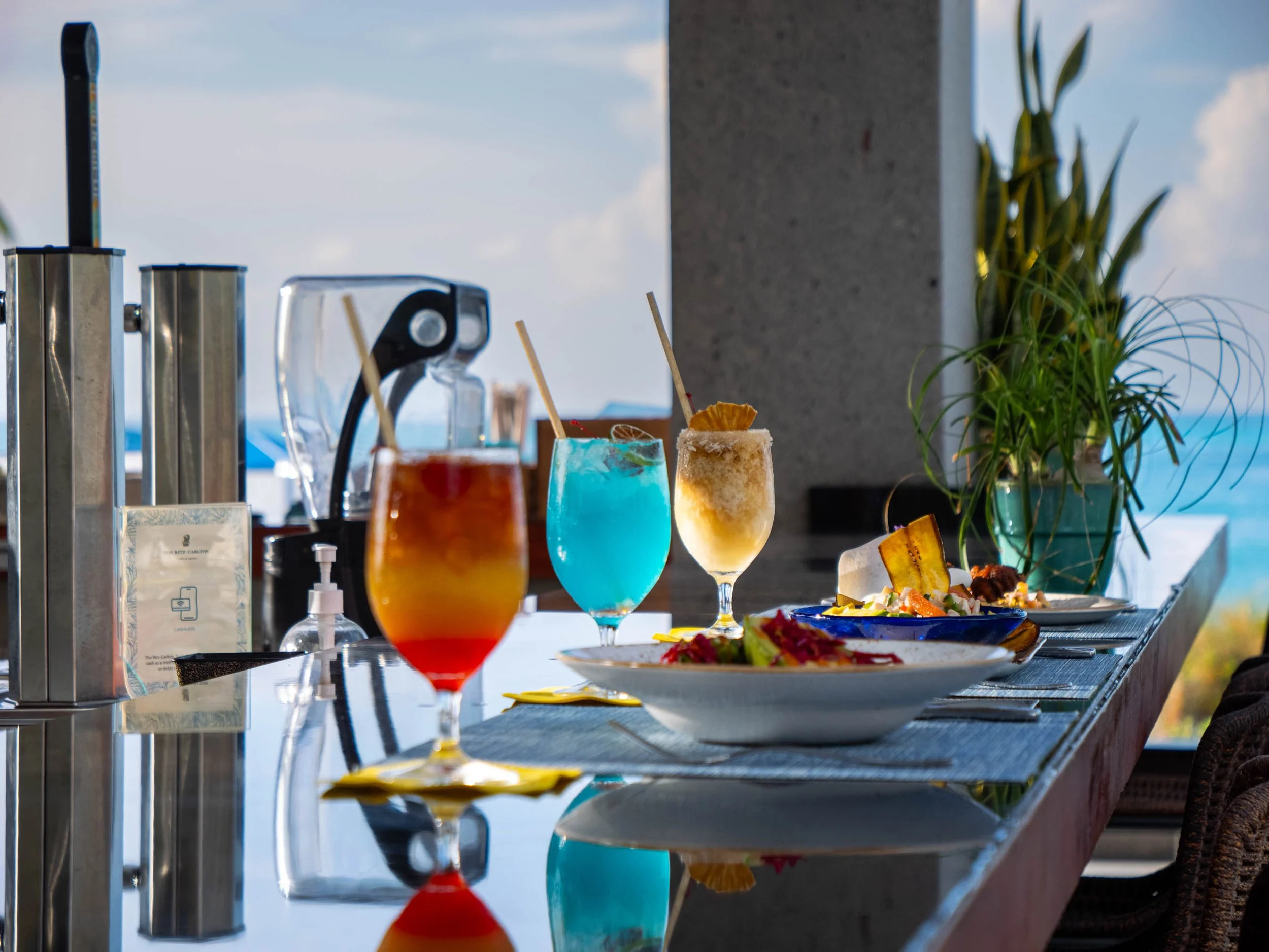 Cocktails and plated dishes on a reflective resort bar at The Ritz-Carlton, Turks and Caicos.