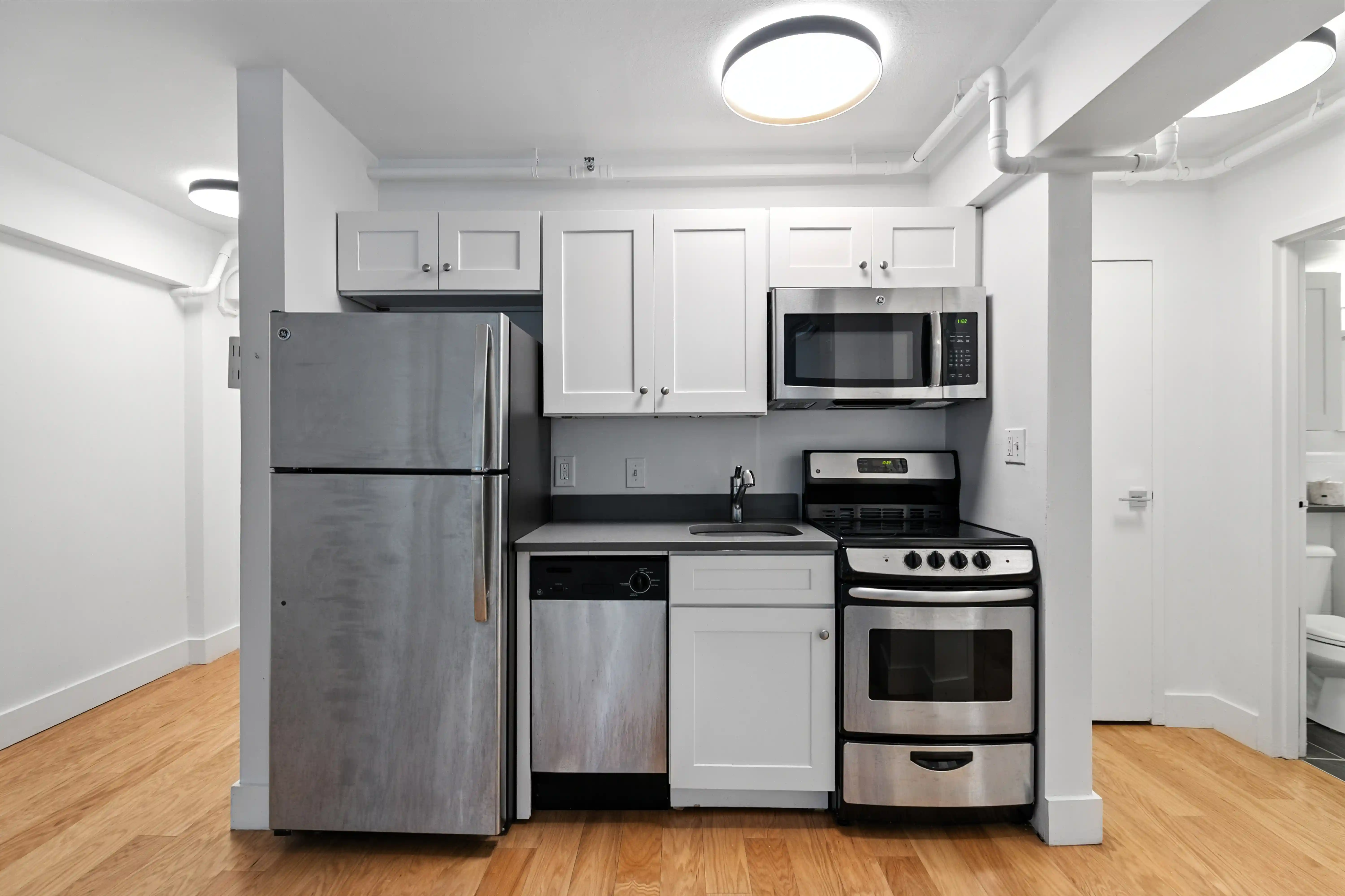 Forte at Beacon kitchen with white cabinets, stainless appliances, and gray counters.