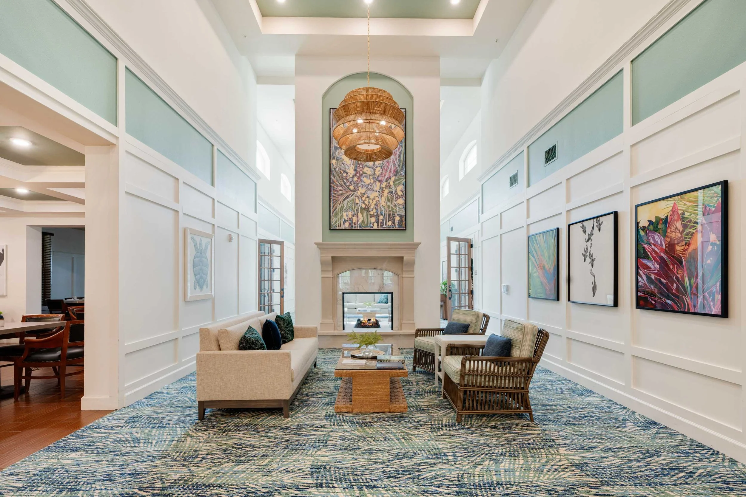 Double-height lounge at The Glades at ChampionsGate with a fireplace and colorful artwork.