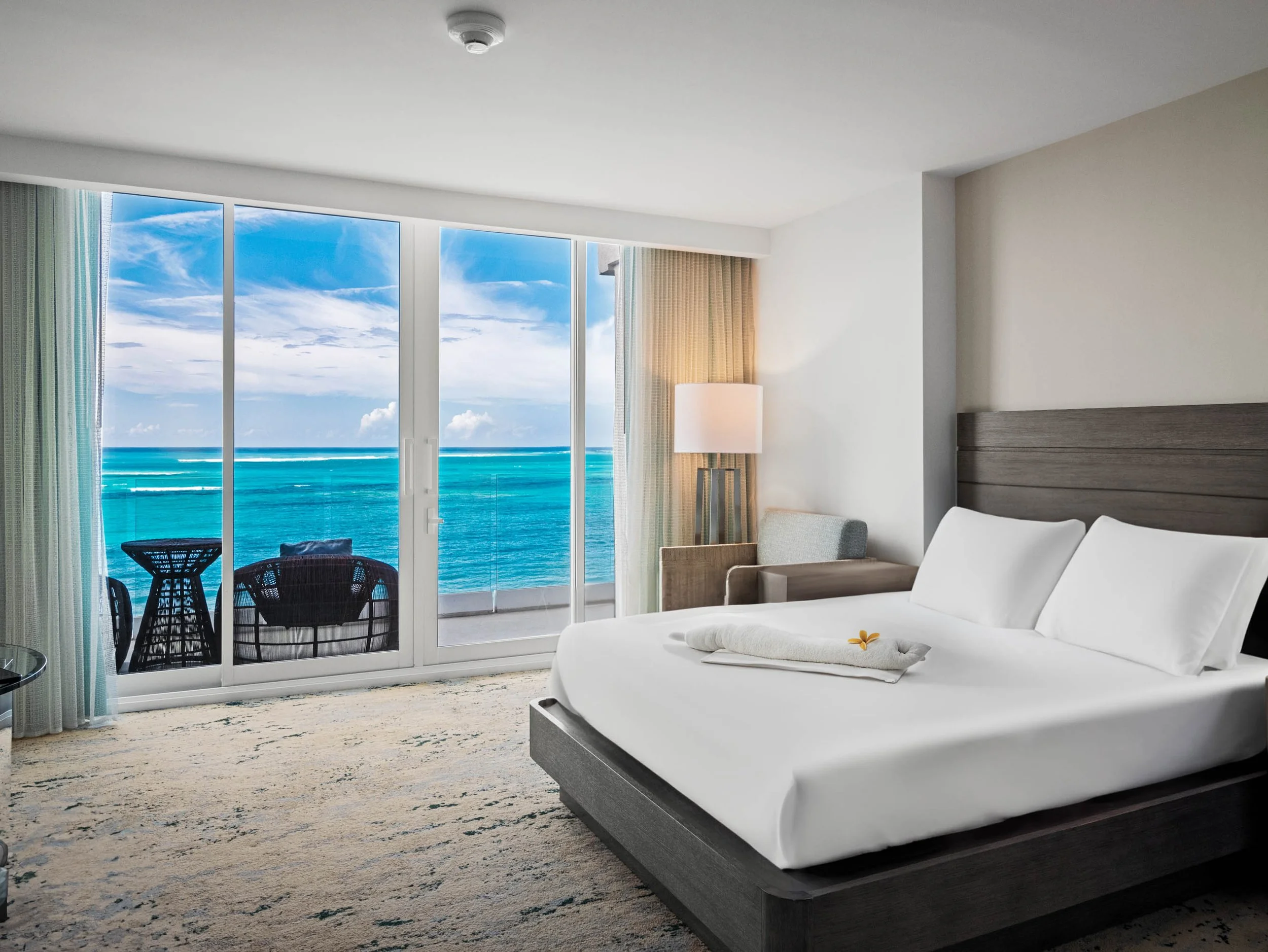 Guest room at The Ritz-Carlton, Turks and Caicos, with a king bed and balcony facing turquoise water.