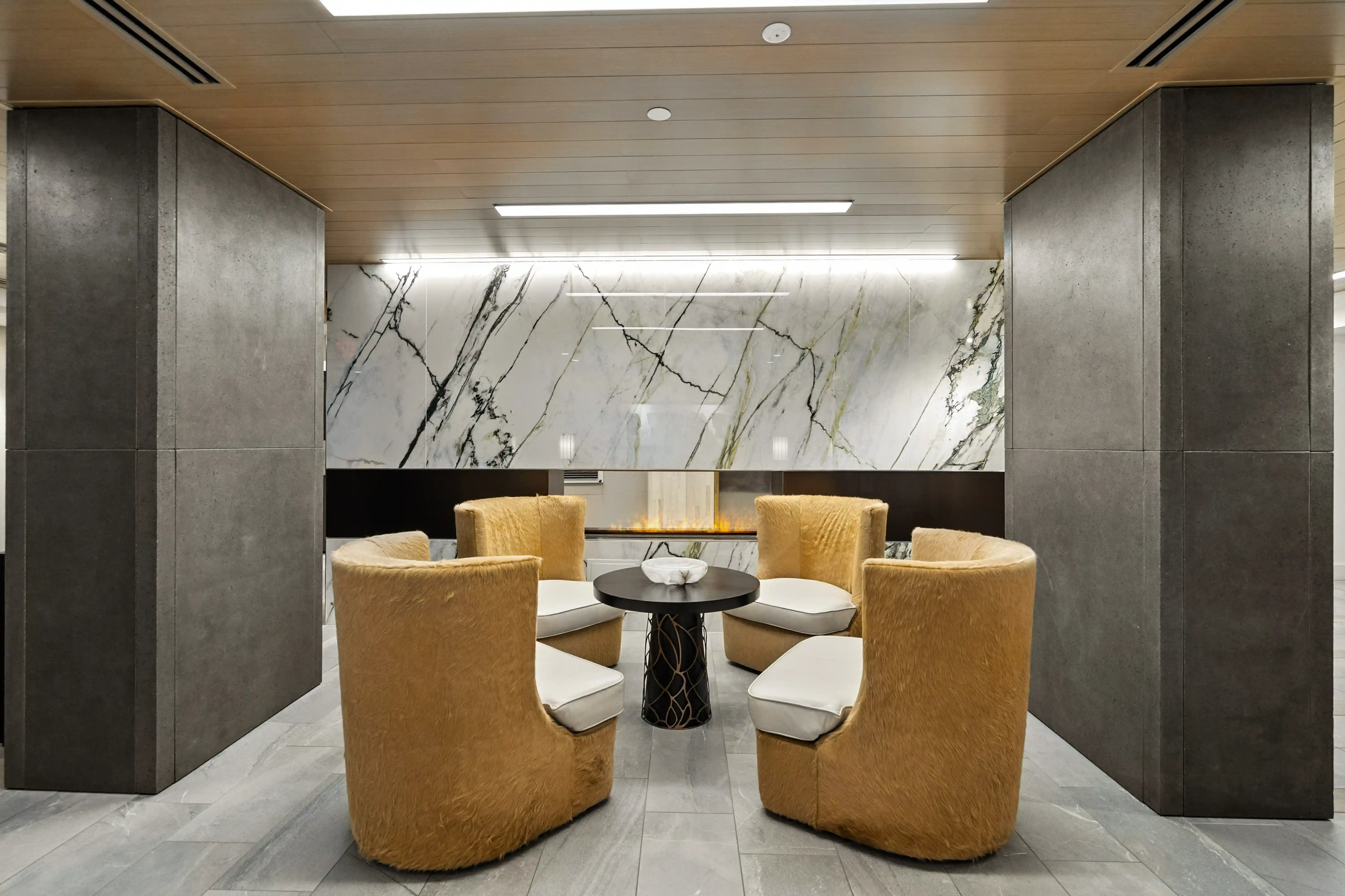 Forte at Beacon lounge with tan chairs arranged around a fireplace and round table.