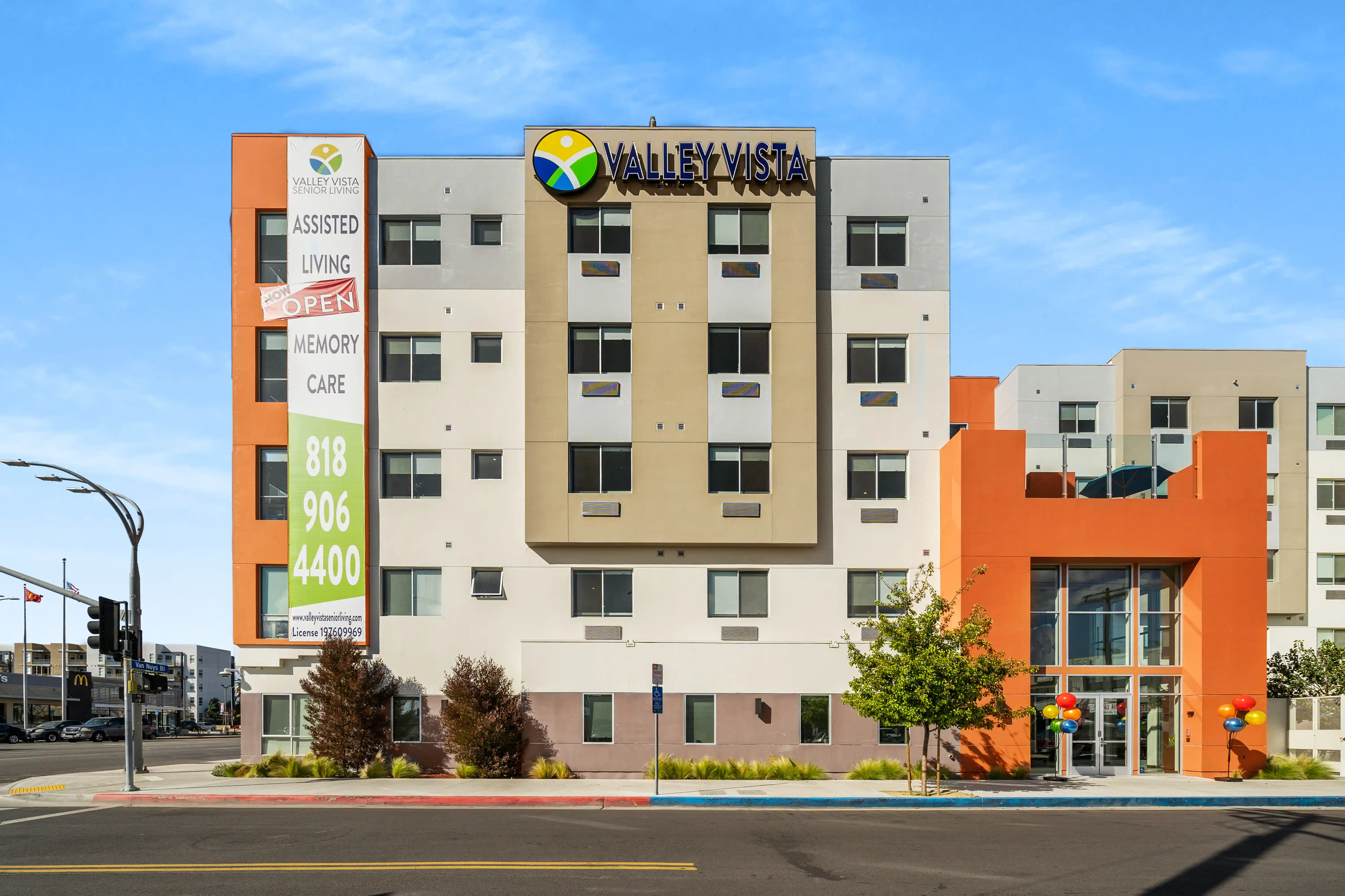 Valley Vista Senior Living exterior with cream and orange facades, signage, and a street-facing entrance.