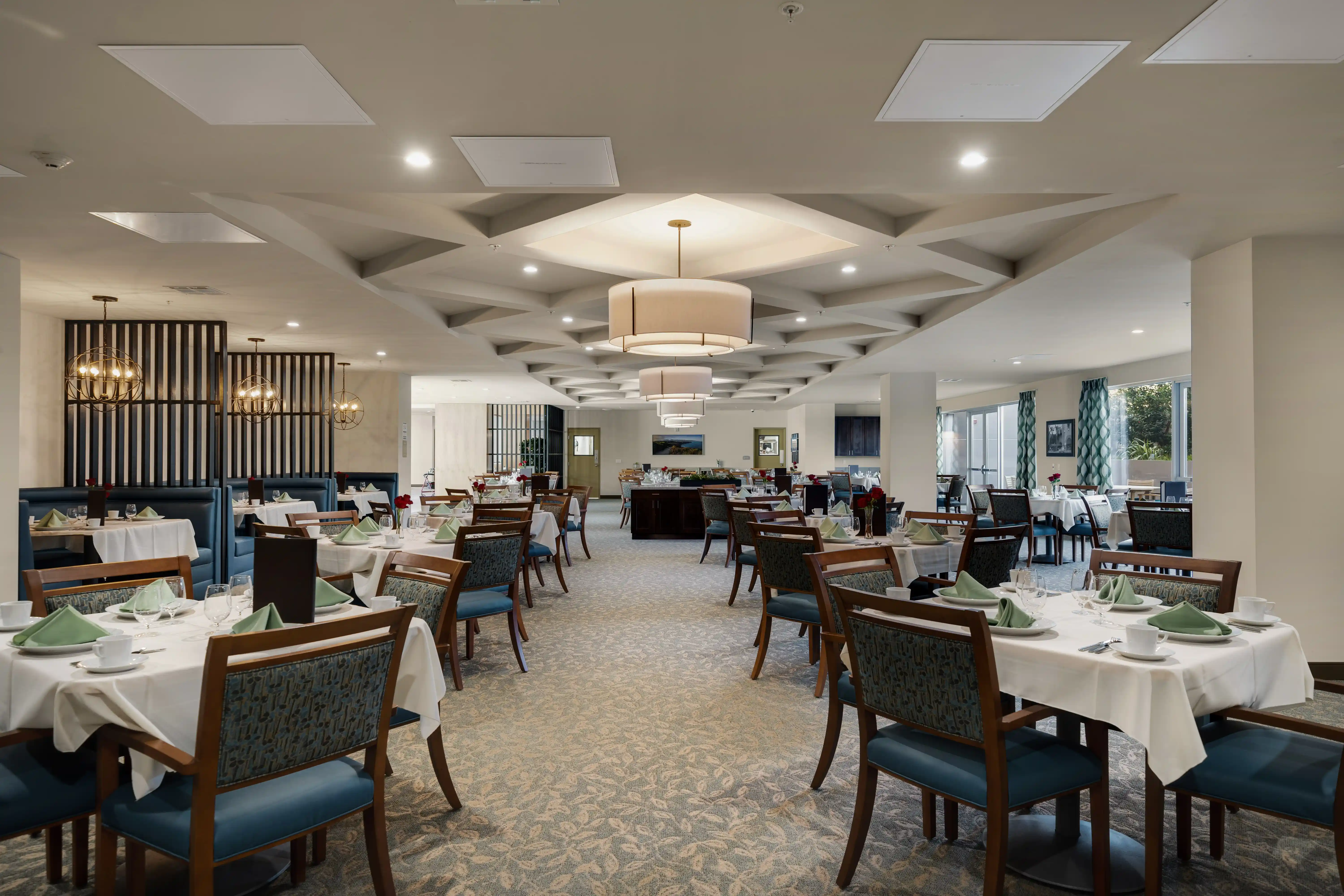 Valley Vista Senior Living dining room with set tables, blue upholstered seating, and pendant lights.