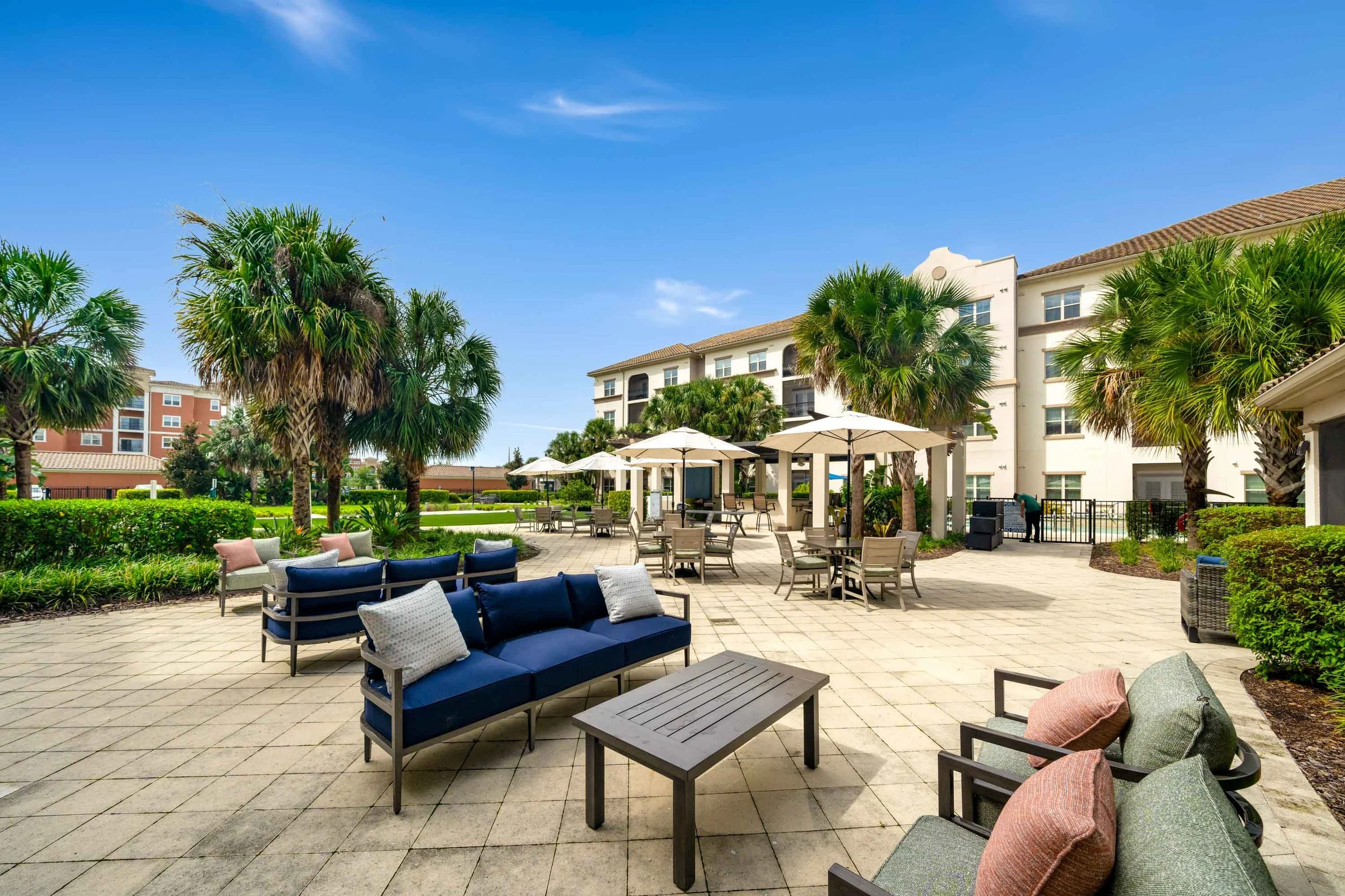 Outdoor terrace at The Glades at ChampionsGate with blue seating, tables, and umbrellas.