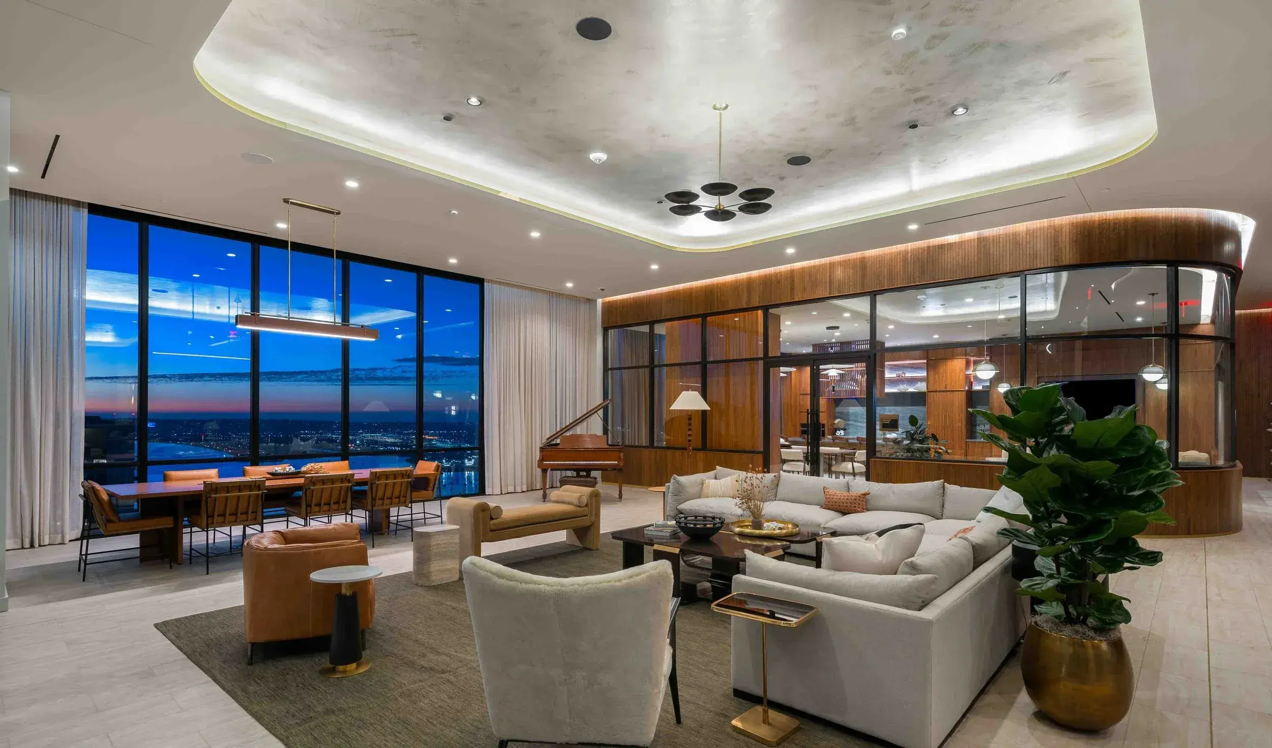 Residential lounge with floor-to-ceiling windows, sofas, plants and layered lighting
