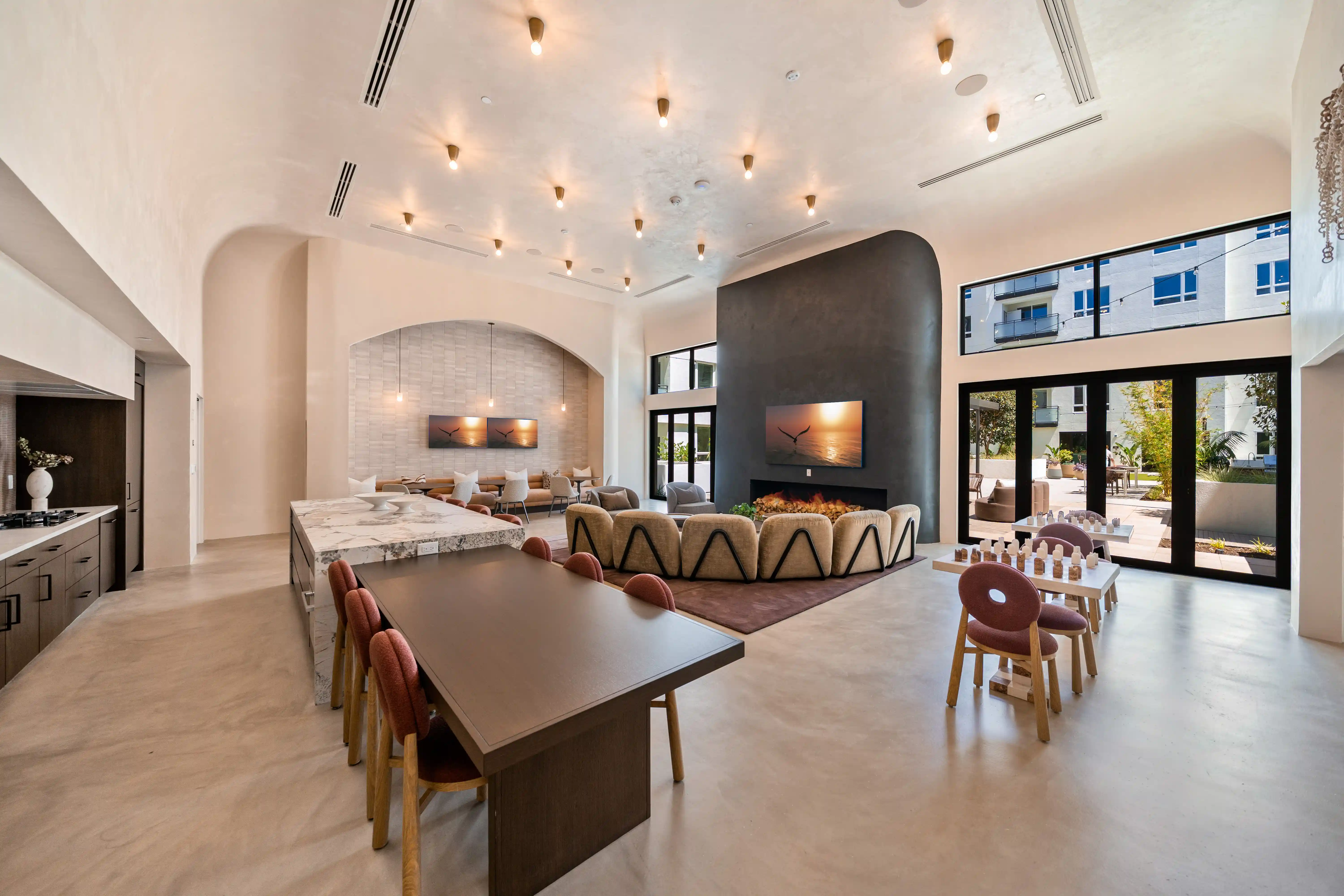 Bright amenity lounge with long tables, seating areas and tall arched ceilings