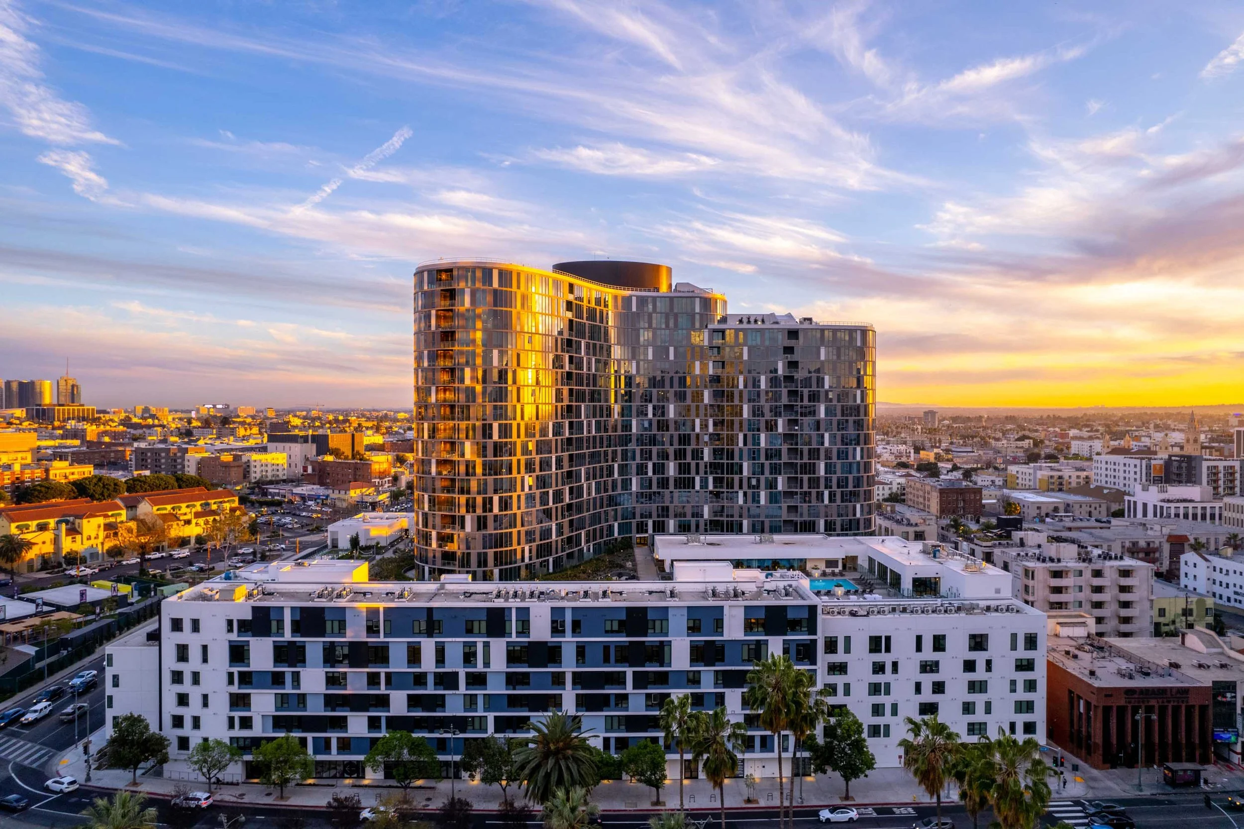 High-rise multifamily property exterior photographed at sunset with neighborhood context