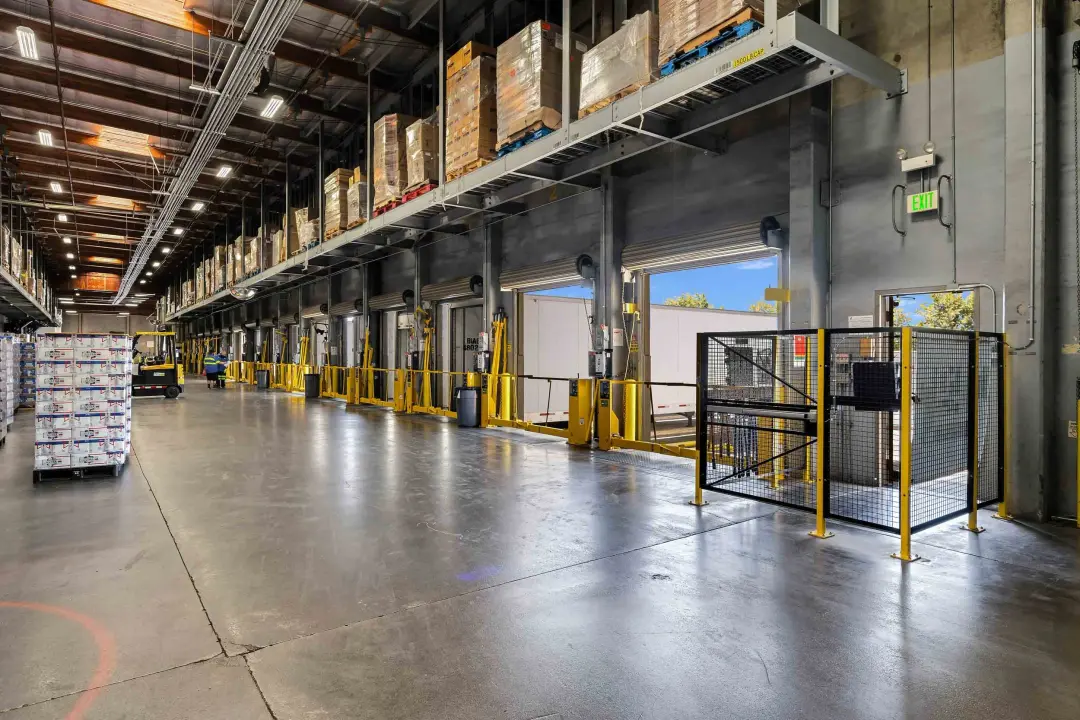 Interior of a logistics warehouse showing long loading dock bays and stored goods