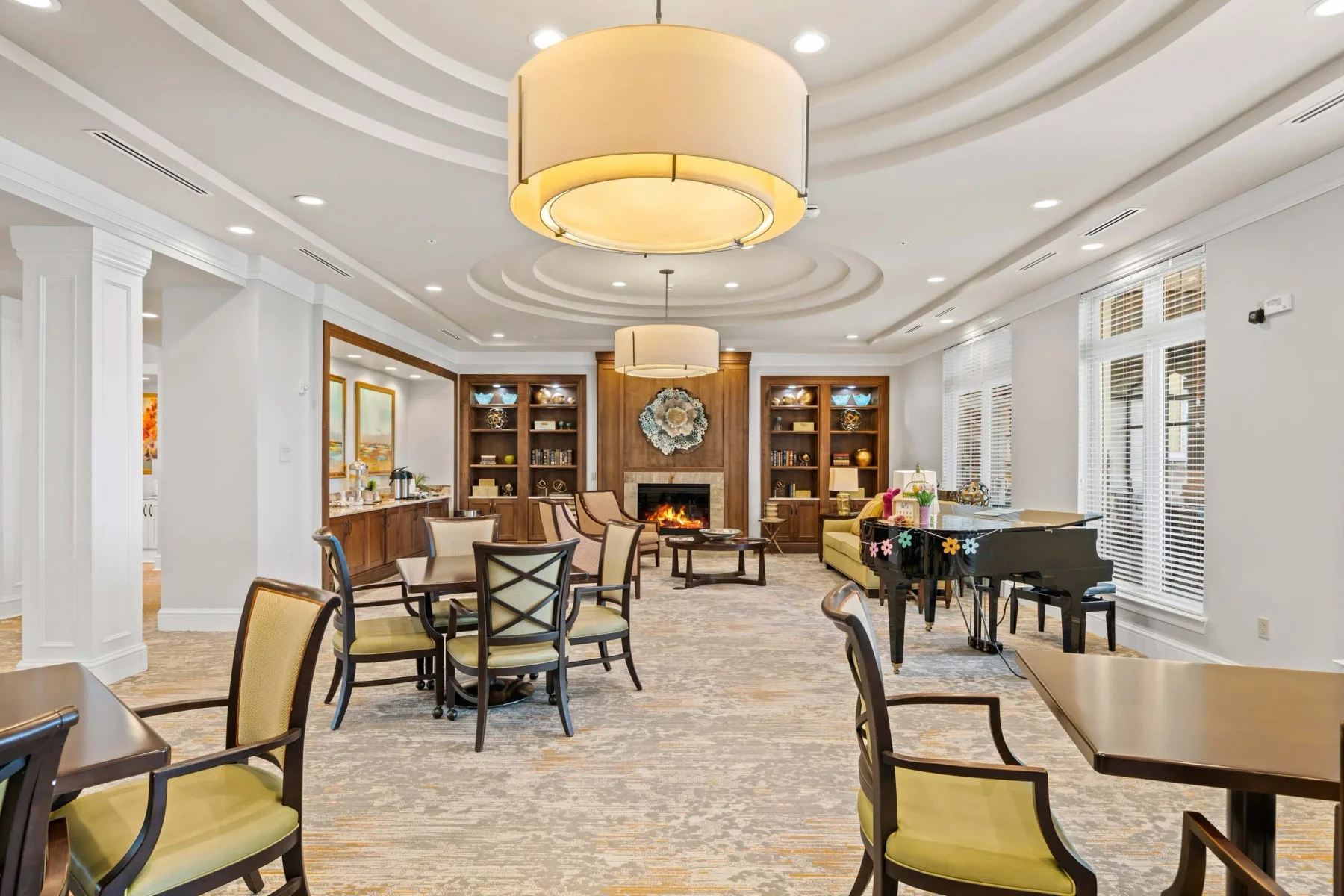 Bright common room with grouped seating, piano and decorative lighting